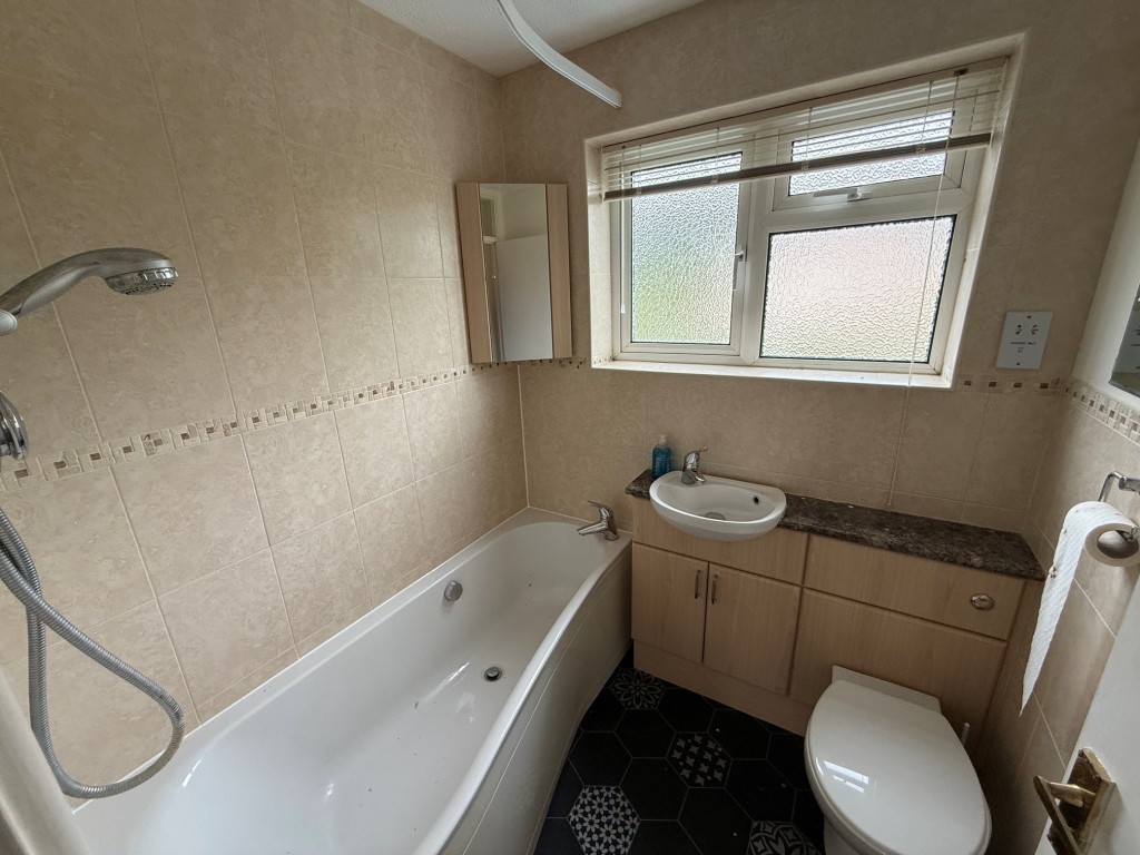 Lot: 114 - THREE-BEDROOM HOUSE FOR IMPROVEMENT AND REPAIR - Bathroom with shower over bath and window to the rear
